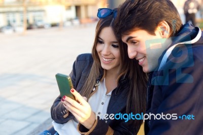 Young Couple Of Tourist In Town Using Mobile Phone Stock Photo