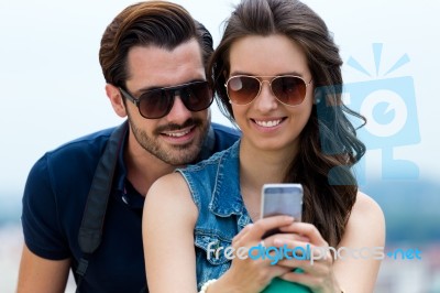 Young Couple Of Tourist In Town Using Mobile Phone Stock Photo