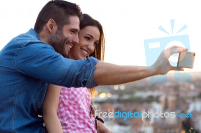 Young Couple Of Tourist In Town Using Mobile Phone Stock Photo