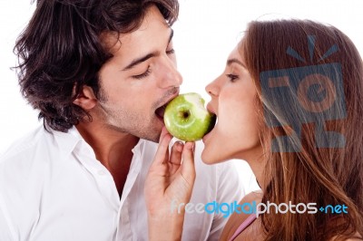 Young Couple Playfully Biting Green Apple Stock Photo