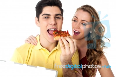 Young Couple Sharing A Pizza Slice Stock Photo