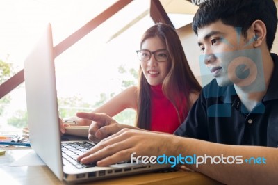 Young Couple Studying In Living Room With Stack Of Texts On Tabl… Stock Photo