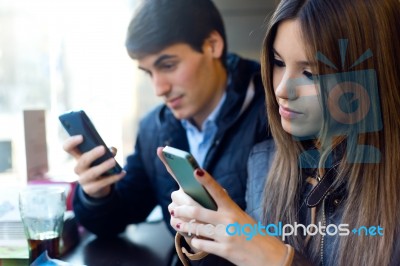 Young Couple Using Mobile Phone In Cafe Stock Photo