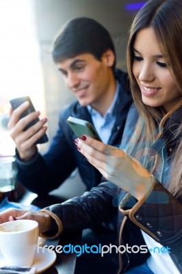 Young Couple Using Mobile Phone In Cafe Stock Photo