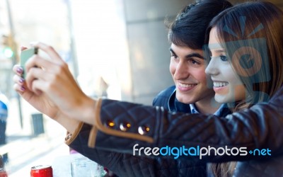 Young Couple Using Mobile Phone In Cafe Stock Photo