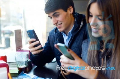 Young Couple Using Mobile Phone In Cafe Stock Photo