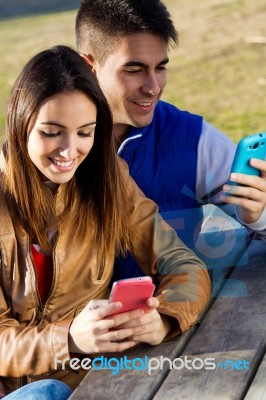 Young Couple With Smartphones In The Park Stock Photo