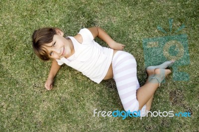 Young Cute Girl Lying On The Grass Stock Photo