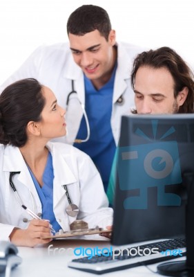 Young Doctors Team Discussing And Making Notes From Computer Stock Photo