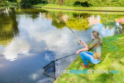 Young Dutch Woman At Waterside With Fishing Rod And Net Stock Photo