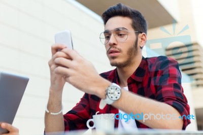 Young Entrepreneur Using His Mobile Phone At Coffee Shop Stock Photo