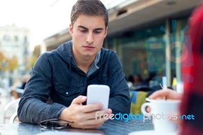 Young Entrepreneur Using His Mobile Phone At Coffee Shop Stock Photo