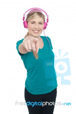 Young Girl Enjoying Music And Pointing At You Stock Photo