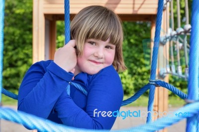 Young Girl Hanging In Web Of Blue Ropes Stock Photo