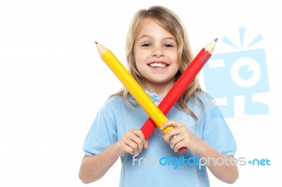 Young Girl Holding Big Red And Yellow Pencils Stock Photo