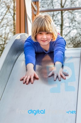 Young Girl Lies Forward On Slide Stock Photo