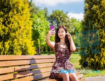 Young Girl Making Selfie Sitting On A Park Bench Stock Photo