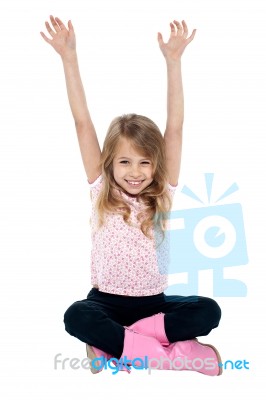 Young Girl Seated On Floor Posing With Raised Arms Stock Photo