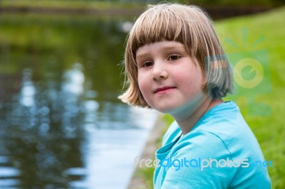 Young Girl Sitting At Pond Stock Photo