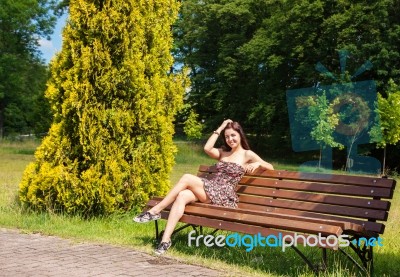 Young Girl Sitting On A Park Bench Stock Photo