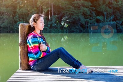 Young Girl Sitting On A Pier Stock Photo