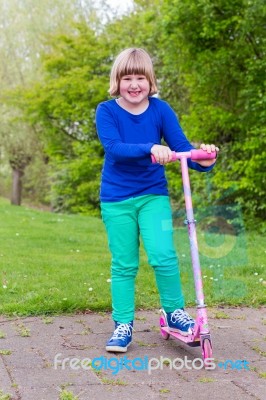 Young Girl Standing With Pink Scooter Stock Photo