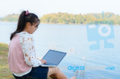 Young Girl With Laptop Sitting On The Riverbank Stock Photo