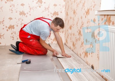 Young Handyman Installing Wooden Floor Stock Photo