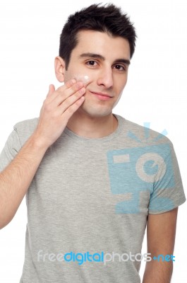 Young Man Applying Cream Lotion Stock Photo