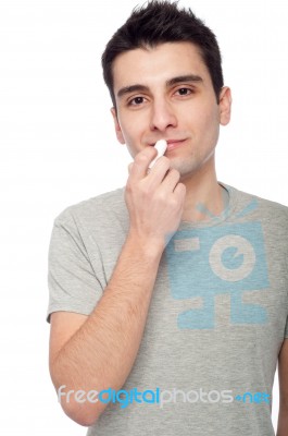 Young Man Applying Lip Balm Stock Photo