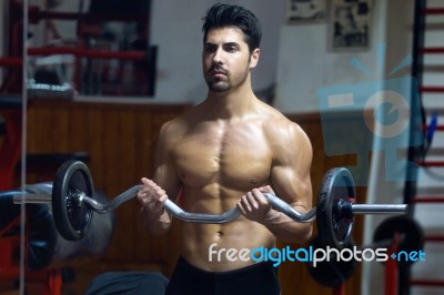 Young Man Doing Heavy Weight Exercise In Gym Stock Photo