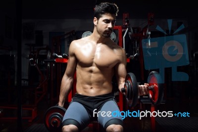 Young Man Doing Heavy Weight Exercise In Gym Stock Photo