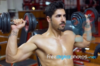 Young Man Doing Heavy Weight Exercise In Gym Stock Photo