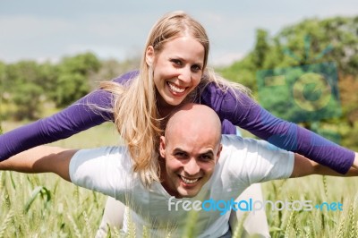 Young Man Giving Shoulder Ride To Her Girlfriend Stock Photo