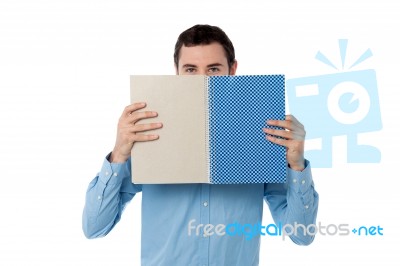 Young Man Hiding His Face With Notebook Stock Photo