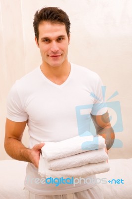 Young Man Holding Stack Of Fresh Towels Stock Photo