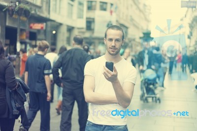 Young Man In City With Mobile Phone Stock Photo