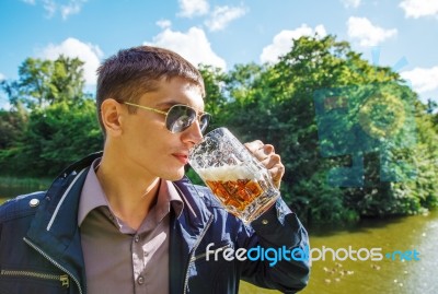 Young Man In Sunglasses Is Drinking Beer In The Park Stock Photo