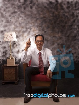 Young Man In White Shirt Sitting On Red Sofa Stock Photo