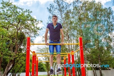 Young Man Is Practicing On A Horizontal Bar Stock Photo