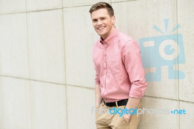 Young Man Posing Smartly Against Wall Stock Photo