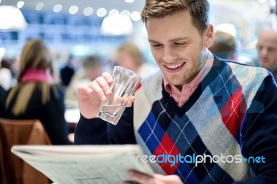 Young Man Reading Newspaper At Cafe Stock Photo