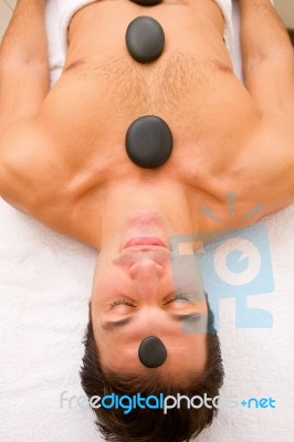 Young Man Receiving Hot Stone Treatment Stock Photo