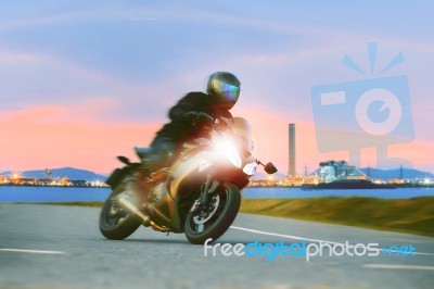 Young Man Riding Sport Touring Motorcycle On Asphalt Highways Against Beautiful Lighting Of Urban Industry Scene Use As Modern People Lifestyle And Holiday Activities Stock Photo