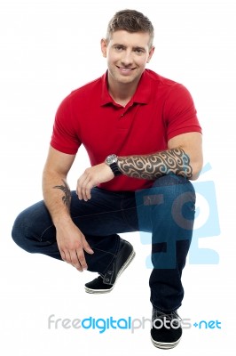 Young Man Squatting On Floor Stock Photo