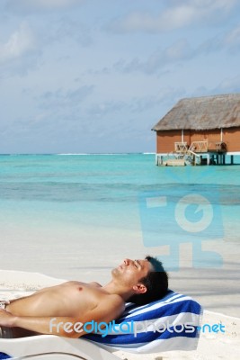 Young Man Sunbathing In A Maldivian Island Beach Stock Photo