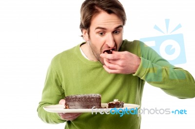 Young Man Tasting Chocolate Cake In Hurry Stock Photo