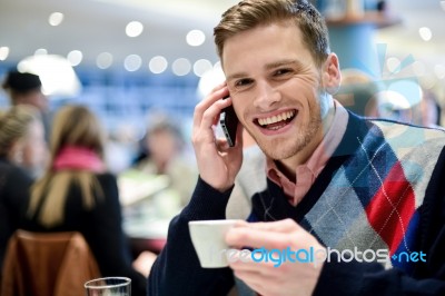 Young Man Using Mobile Phone In Cafe Stock Photo