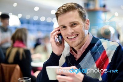 Young Man Using Mobile Phone In Cafe Stock Photo