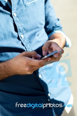 Young Man Using Mobile Phone In The Street Stock Photo